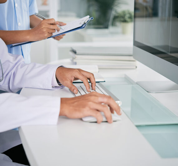 Cropped image of doctor working on computer at his table